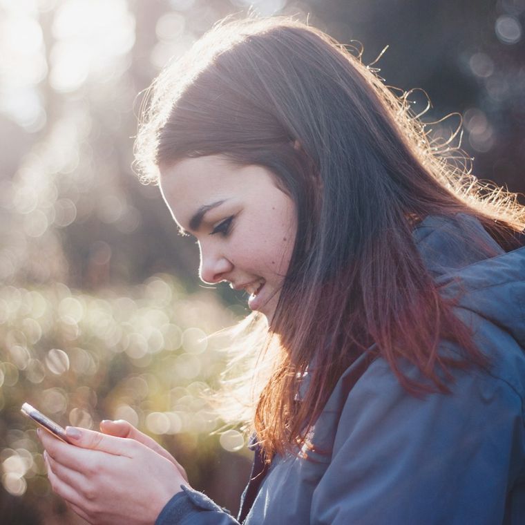 A woman smiling while booking on her phone